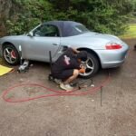 Mobile tyre technician balancing a car wheel using a balancing machine