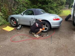 Mobile tyre technician balancing a car wheel using a balancing machine