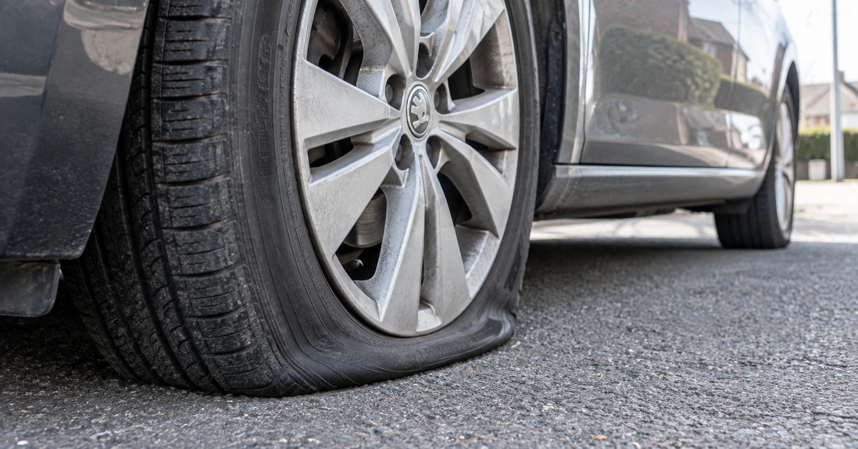 Completely flat car tyre compressed against the road while the vehicle is parked