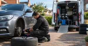 Professional mobile tyre fitter replacing a damaged car tyre on a residential driveway in Reading