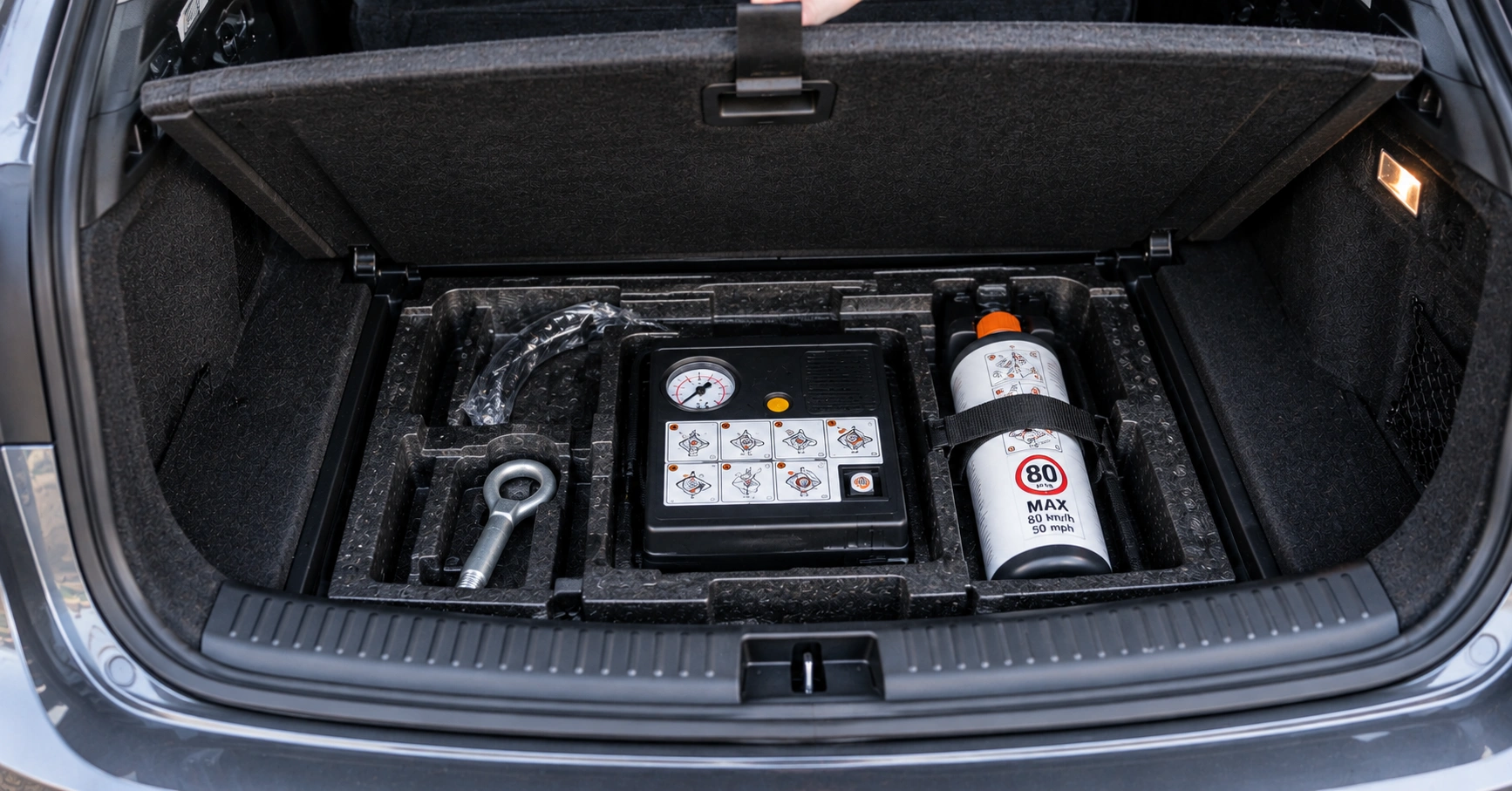 Car boot with the floor lifted showing a tyre sealant and inflation kit instead of a spare wheel