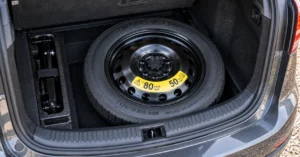 Space saver spare wheel in a car boot showing the temporary-use maximum speed warning